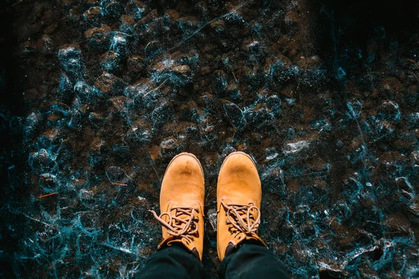 Um par de botas castanhas no fundo com textura de gelo. Islândia. Espaço de cópia — Fotografia de Stock