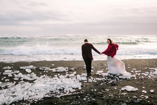 Çift düğün birlikte siyah kum plaj, İzlanda üzerinde yürüyor. Sanat — Stok fotoğraf