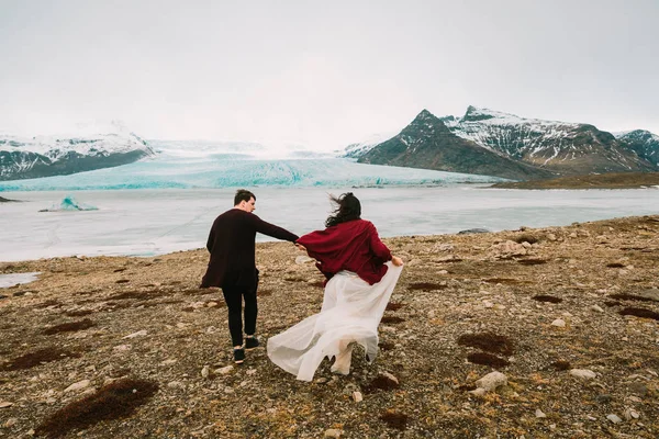 冰岛在冰川泻湖举行婚礼。新娘和新郎一起奔跑。后视图 — 图库照片