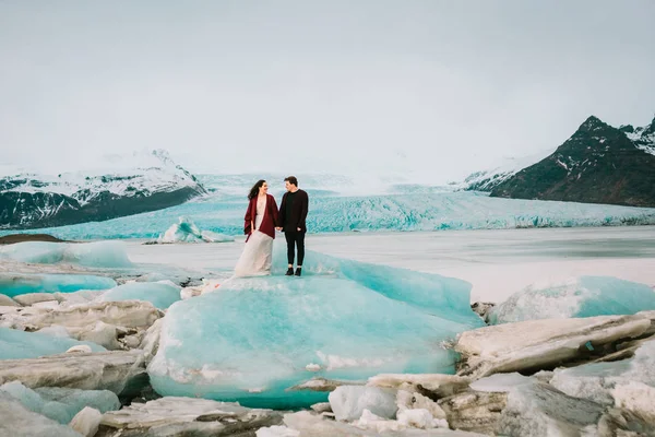 Les jeunes mariés se tiennent ensemble sur l'iceberg bleu. Islande Mariage dans la lagune des glaciers . — Photo