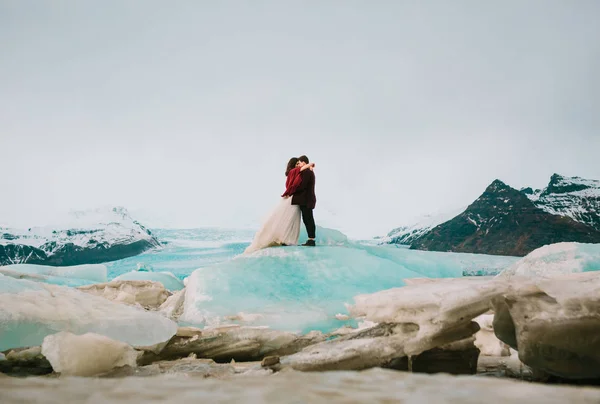 Panna młoda i pan młody uściski na niebieski góry lodowej. Islandia ślub w Laguna. — Zdjęcie stockowe