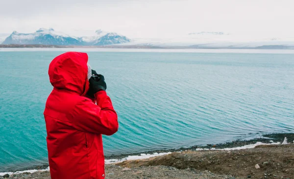 Nature travel photographer, person in red jacket taking photo of river in Iceland — Stock Photo, Image