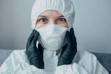 Tıbbi virüs maskeli bir virüs bilimci, viral koruyucu giysi ve siyah eldivenler maskeyi ayarlar ve koronavirüsün sonuçlarını izole eder. Koruma maskesini karantinaya alıp giydirdiler.