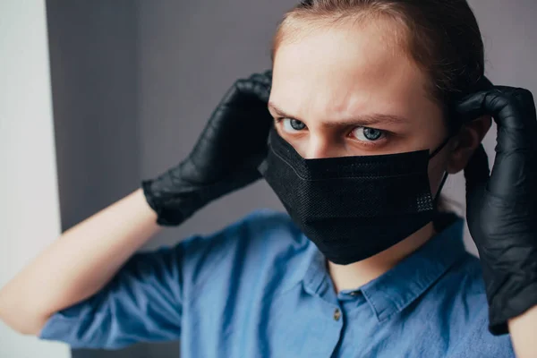 a nurse in a black mask and medical gloves looks away and thinks how to protect people from the coronavirus. Doctor in clinic thinks how to stop virus epidemic.