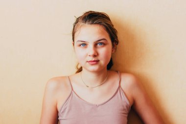 Mavi gözlü beyaz kız kameraya bakıyor. Sarı arka planda, basit bir ev içinde genç bir kız uykusunda kameraya bakıyor. Kadınların doğal güzellikleri daha yeni uyandı.