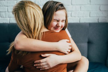 Anneler Günü. Güzel genç bir kadın ve sevimli küçük kızı sarılıyor ve gülümsüyor. Anne kızına nazikçe sarıldı, kız yanağına göz ucuyla sarıldı.. 