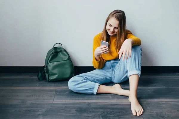 Genç Kız Cep Telefonuna Bakıyor Ahşap Zeminde Oturmuş Gülümsüyor Sarı Stok Resim