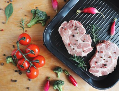 Taze domuz biftek ızgara tava üzerinde. Organik domates, biberiye, karabiber karışımı. Kahverengi ahşap zemin