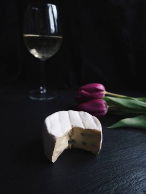  cam beyaz şarap ve taze mor laleler ile peynir kesti. Siyah taş arka plan. Fransızca peynir, gurme mutfağı. Yan görünüm