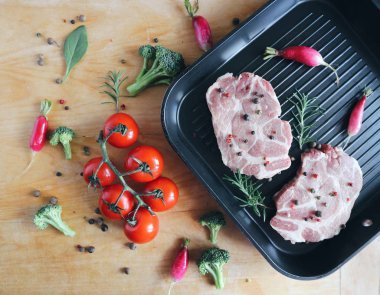 Taze domuz biftek ızgara tava üzerinde. Organik domates, biberiye, karabiber karışımı. Kahverengi ahşap zemin