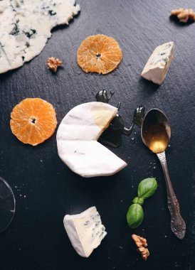 Çeşitli peynir, fındık, taze meyve ile siyah bir taş tabloda tatlım. Gorgonzola, Brie, rokfor peynir mavi. Çeşitli aperatifler ve mezeler. Üstten Görünüm. Gurme mutfağı. Lezzetli yemekler.