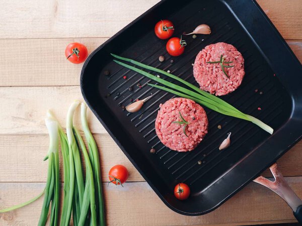 Minced meat,  spices, cherry tomatoes, garlic. White wooden background. Raw ingredients ready for cooking. Closeup. Space for text. Delicious tartar.