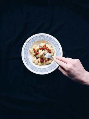 Çatal ve İtalyan geleneksel gnocchi tutan erkek el. Kuru domates, Parmesan peyniri, erimiş sarımsak ile geleneksel İtalyan gnocchi otlar ile tereyağı. 
