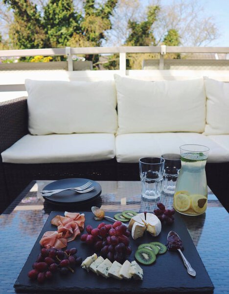 крупным планом фото вкусного набора сыра с гулом и винограда с лимонадным соком на черной доске на фоне стола
