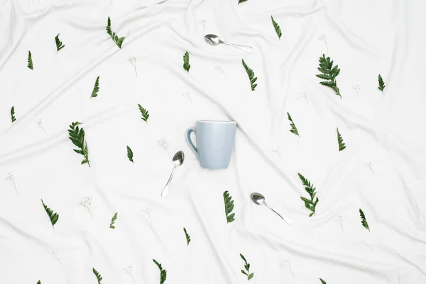 blue mug on white cloth with leaves