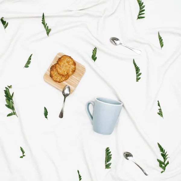 Tasse bleue et biscuits sur tissu blanc — Photo