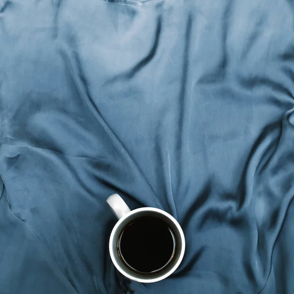 Білий кухоль на синій тканині — стокове фото