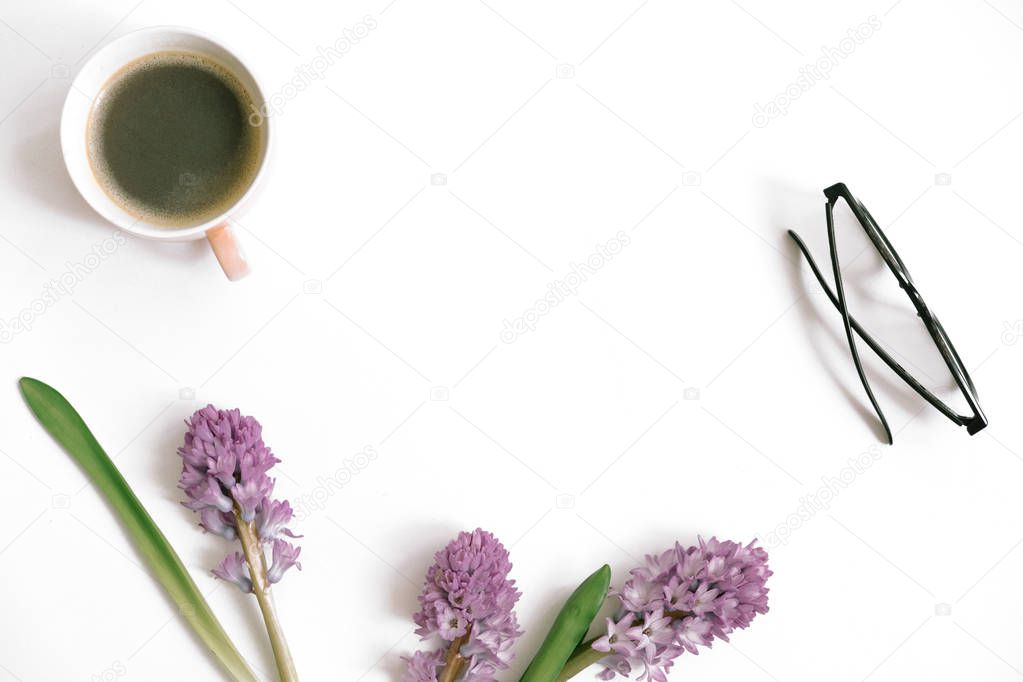 Lilac hyacinth flowers, coffee cup and eyeglasses on white background. Flat lay, top view