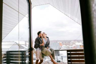 Evde güzel çift birlikte. Güzel kadın ve şık rahat kıyafetler giymiş çekici bir adam ve bir Balkonda duran ve sarılma paket