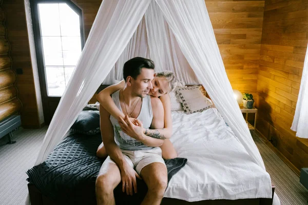 Evde güzel çift birlikte. Güzel kadın ve çekici adam bir yatak üzerinde oturan ve sarılma ev Giyim Giyim Eşyası.