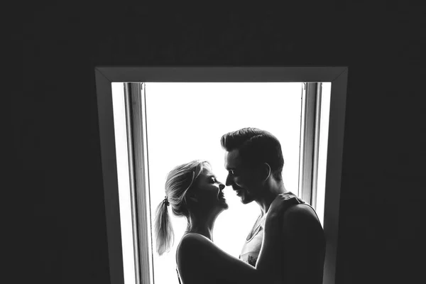 家で一緒に素敵なカップルです きれいな女性と窓の近くに立っている家の服服を着て魅力的な男性 黒と白の写真 — ストック写真