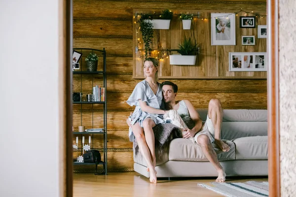 Evde güzel çift birlikte. Güzel bir kadın ve bir kanepe sarılma üzerinde oturan çekici adam şık rahat kıyafetler