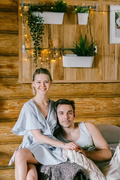 家で一緒に素敵なカップルです きれいな女性とハグ ソファの上に座って魅力的な男性スタイリッシュなカジュアル服 — ストック写真