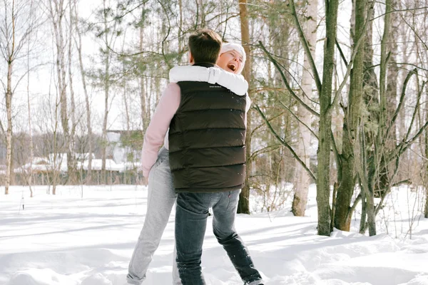 Güzel çift birlikte kar ile oynarken açık havada güneşli bir günde. Güzel kadın ve çekici adam gülüyor ve birbirlerine gülümseyen şık rahat kıyafetler giymiş.