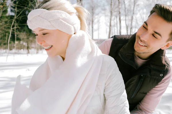Güzel çift birlikte kar ile oynarken açık havada güneşli bir günde. Güzel kadın ve çekici adam gülüyor ve birbirlerine gülümseyen şık rahat kıyafetler giymiş.