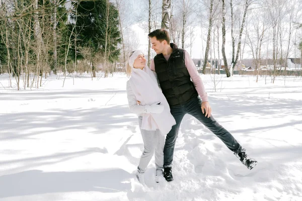 Güzel çift birlikte kar ile oynarken açık havada güneşli bir günde. Güzel kadın ve çekici adam gülüyor ve birbirlerine gülümseyen şık rahat kıyafetler giymiş.