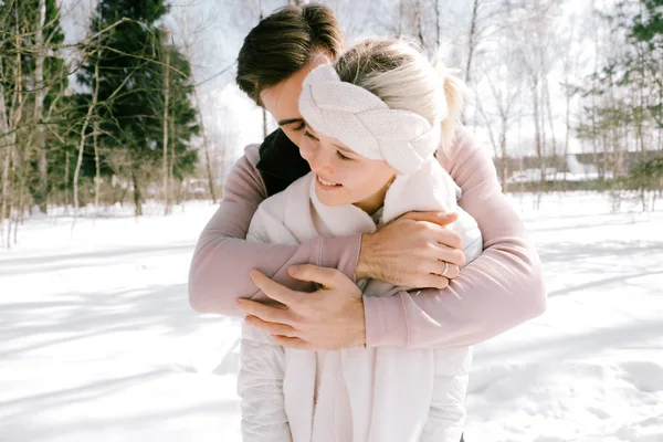 Güzel çift birlikte kar ile oynarken açık havada güneşli bir günde. Güzel kadın ve çekici adam gülüyor ve birbirlerine gülümseyen şık rahat kıyafetler giymiş.
