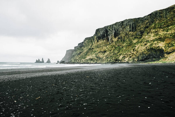 Reynisfjara black sand beach in Vik town in Iceland, surrounded with basalt mountains