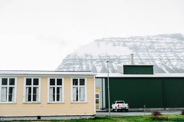 stock image Lonely white house and snow-covered mountain in Iceland. Winter northern scenery 