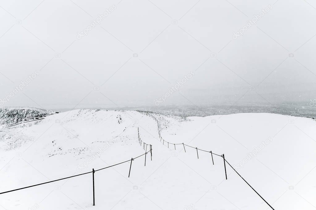 Snowy minimalistic path with a fence high in the mountains. Shot in Iceland near Grabrok volcano