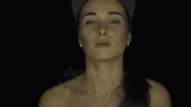 Прекрасна дівчина. Красивий портрет дівчини в бейсбольній шапці на чорному тлі — стокове відео