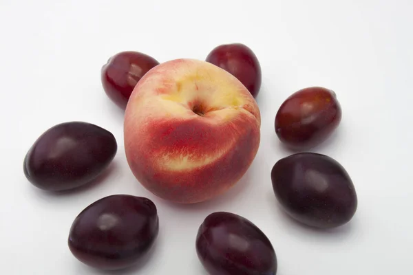 Melocotones y ciruelas sobre un fondo blanco. Ciruelas apetitosas. Fruta madura. Melocotón pequeño —  Fotos de Stock