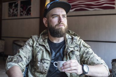 Sakallı bir adam. Bir fincan kahve ile adam.