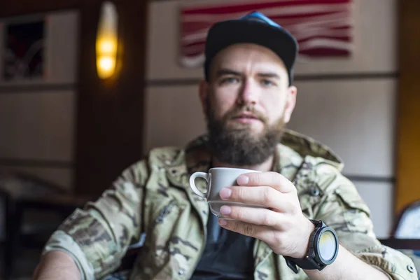Egy szakállas fickó. A fickó egy csésze kávét, nem a fókuszban. — Stock Fotó
