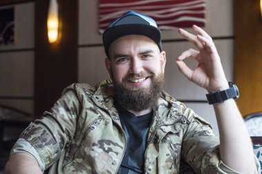 Sakallı bir adam. Adam ok gösterir. 