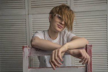 Gözlük takan bir sandalyede bir kız. Bir kız ile bir kısa saç modeli