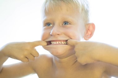 Çocuk beyaz diş gösterir.