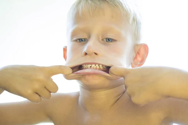 The boy shows white teeth. — Stock Photo, Image