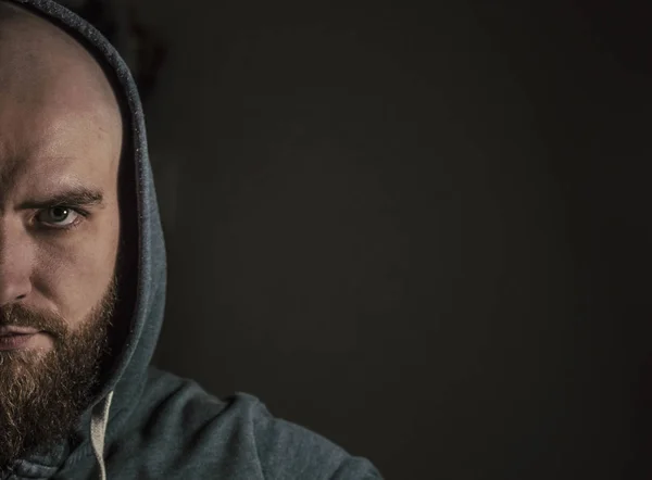 Portrait of a bearded bald man on a black background. Half the f