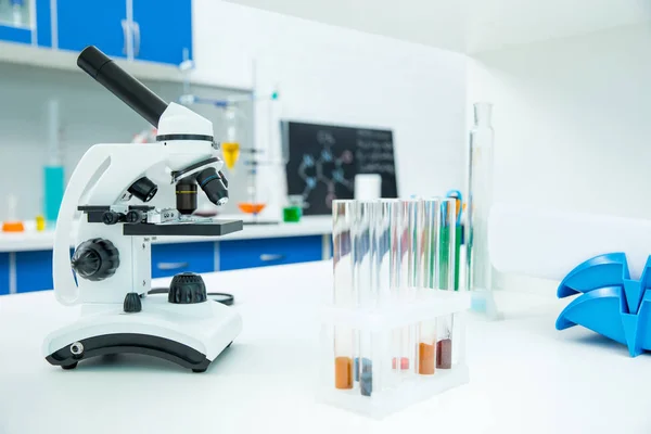 Microscópio e tubos de ensaio em laboratório — Fotografia de Stock