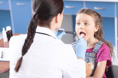 Doctor checking throat of girl clipart