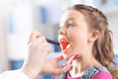 Doctor checking throat of girl clipart