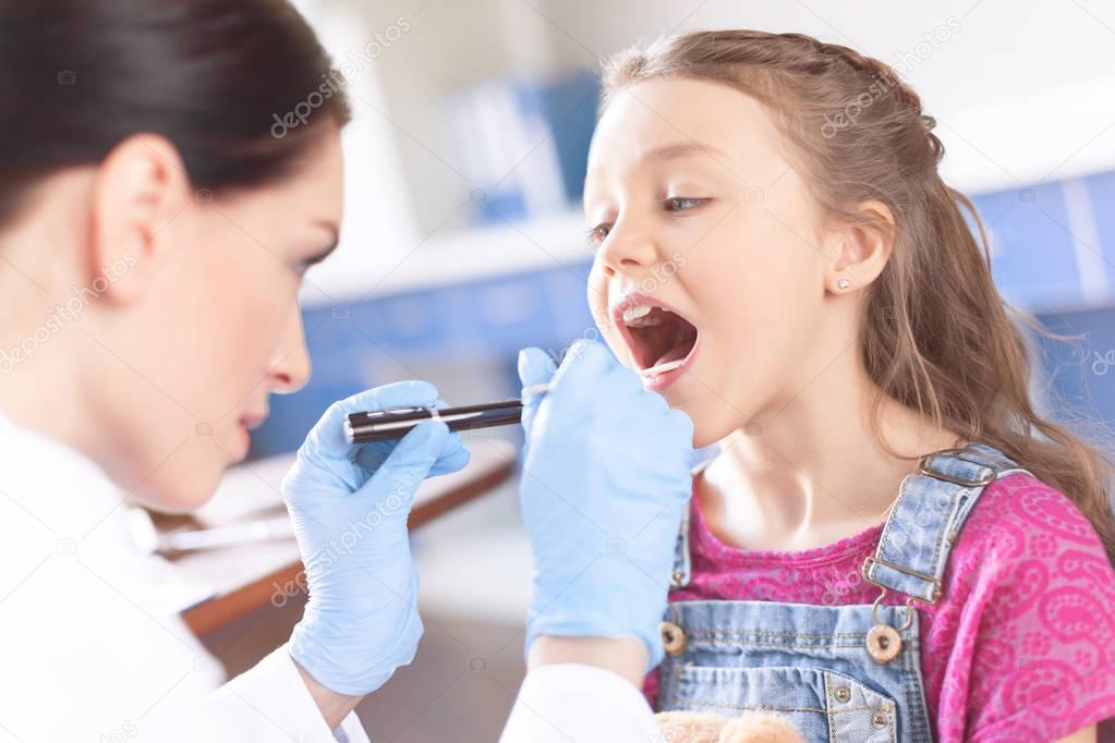 Doctor checking throat of girl