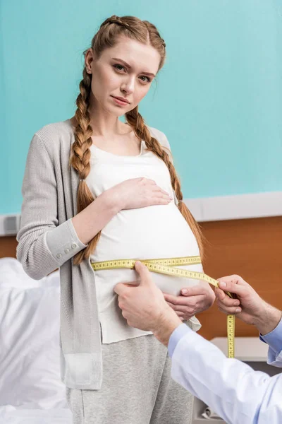 Médico que mede a barriga da mulher grávida — Fotografia de Stock