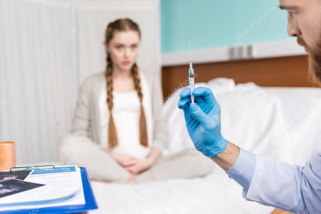 Pregnant woman and doctor with syringe 