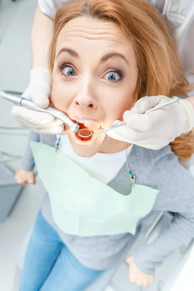 Зубной врач лечит испуганного пациента — стоковое фото